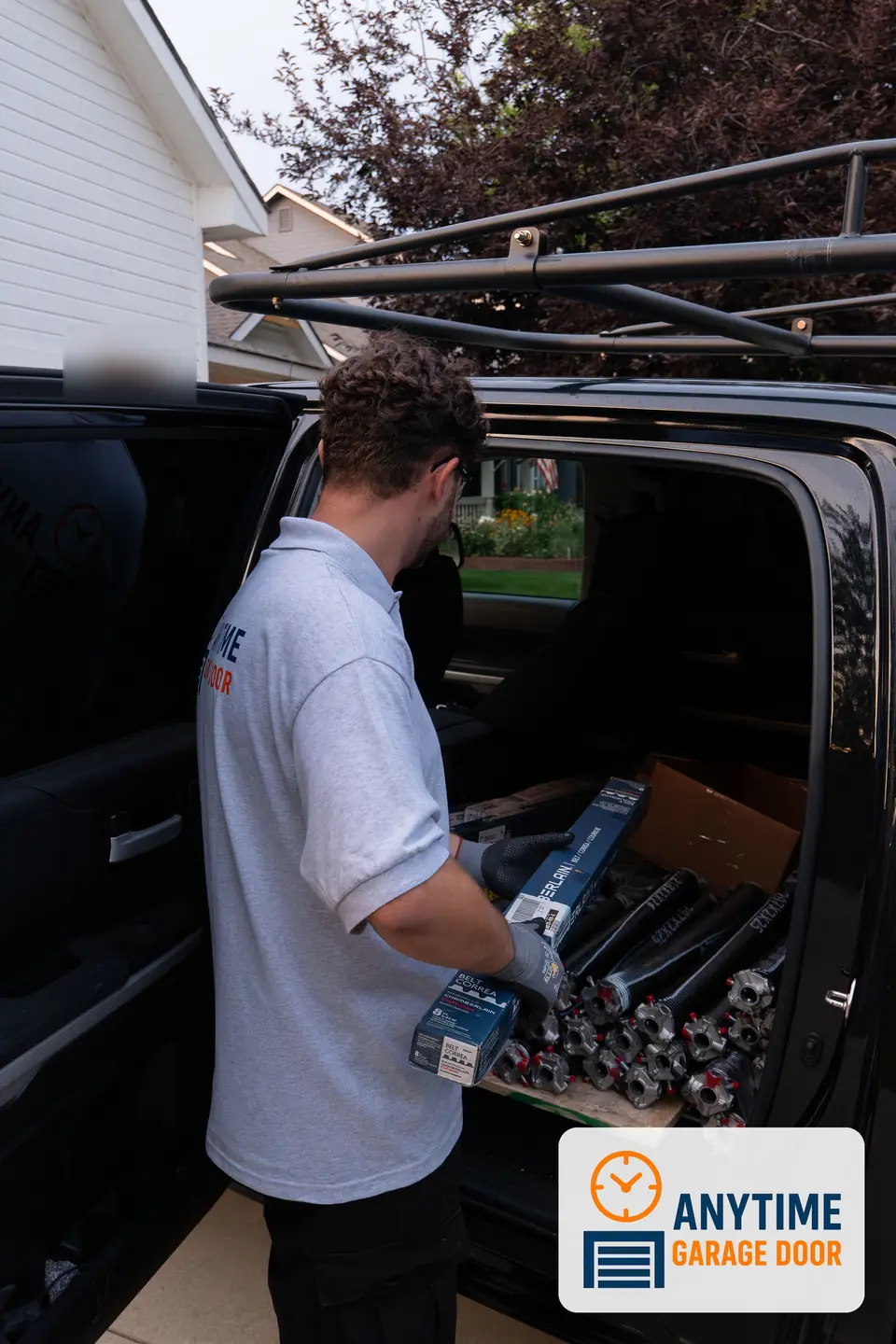 Technician lifts Chamberlain opener belt boxes from a truck back seat stacked with torsion springs.